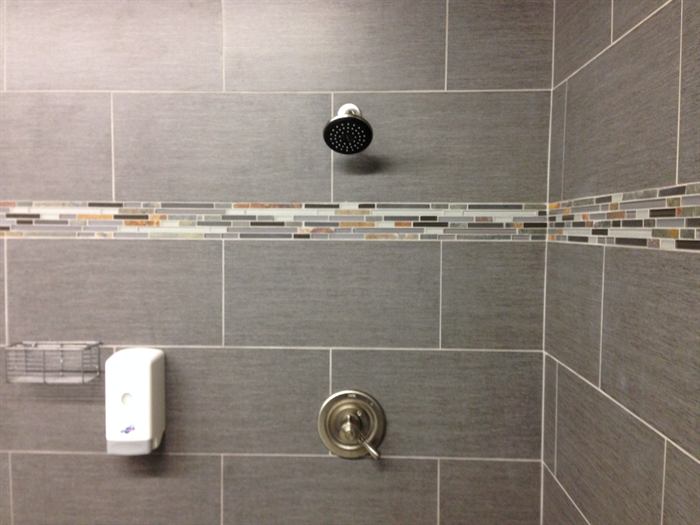 Shower wall of gray linen texture rectangular tile with a multicolor glass and stone mosaic accent band