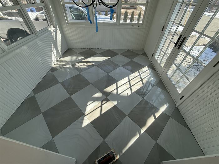 A tiled entryway floor in a grey and white diamond pattern