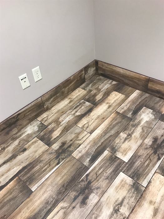 Rustic gray and brown wood look plank tile floor with matching tile baseboard