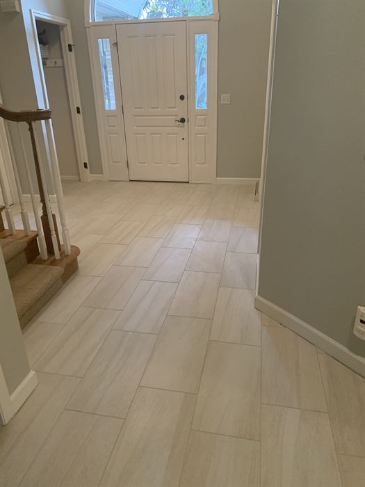 Light gray stone look rectangular floor tile in an offset layout through a front entryway
