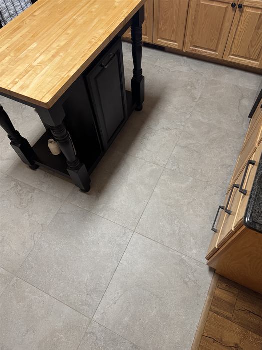 Large square gray stone look floor tile in a kitchen with oak cabinets