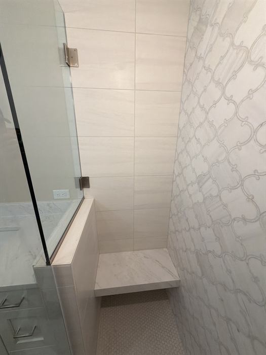 A shower tiled in arabesque lantern tile with a built in bench