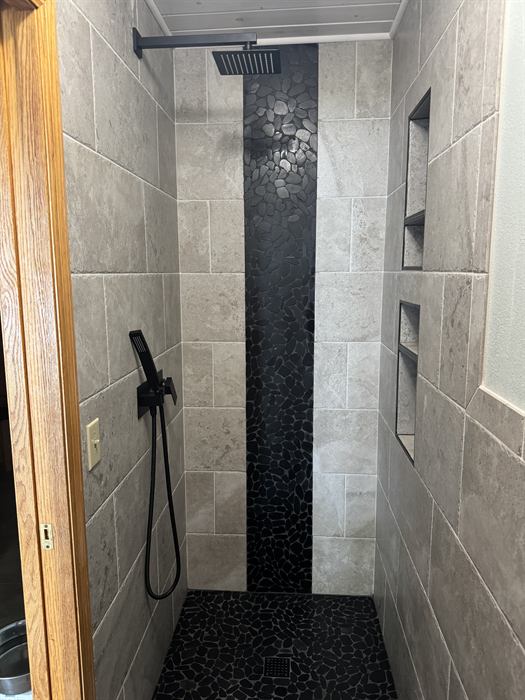 A finished shower with a dark linear mosaic feature strip